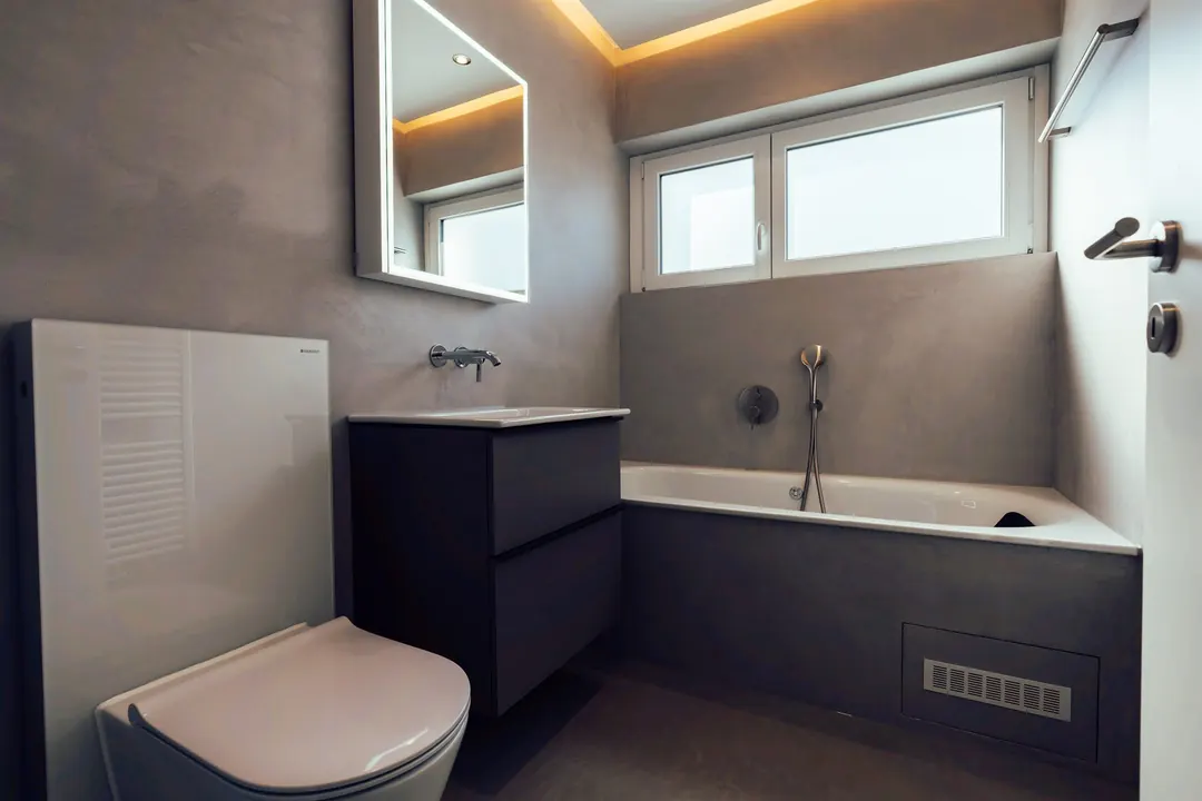 Modern saniertes Badezimmer mit fugenlosen Wänden und beleuchtetem Spiegelschrank