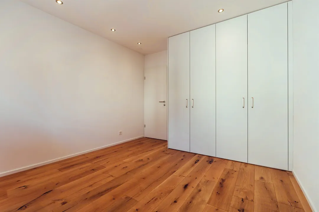 Renoviertes Zimmer mit weissem Einbauschrank und Eichenparkett
