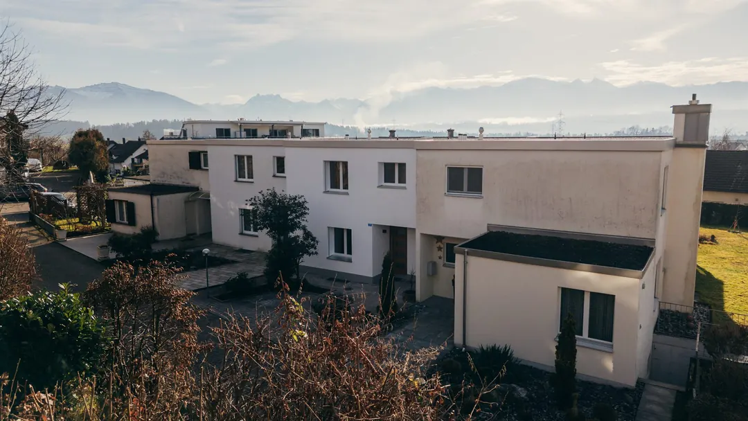 Drohnenaufnahme des renovierten Reihenhauses vor Alpenkette