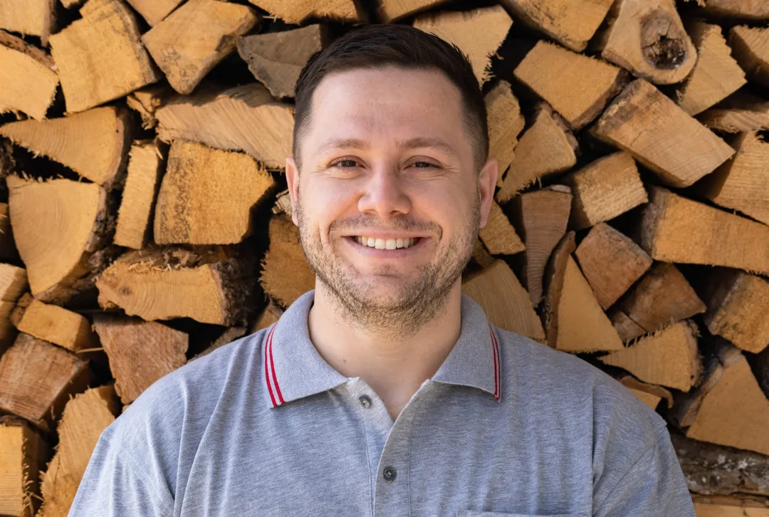 Renato Suli, Allrounder bei ISI-FIX, vor Brennholzwand